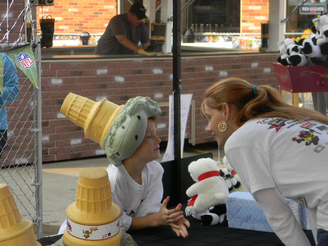 Young woman talking to a child with a ice cream cone hat on his head